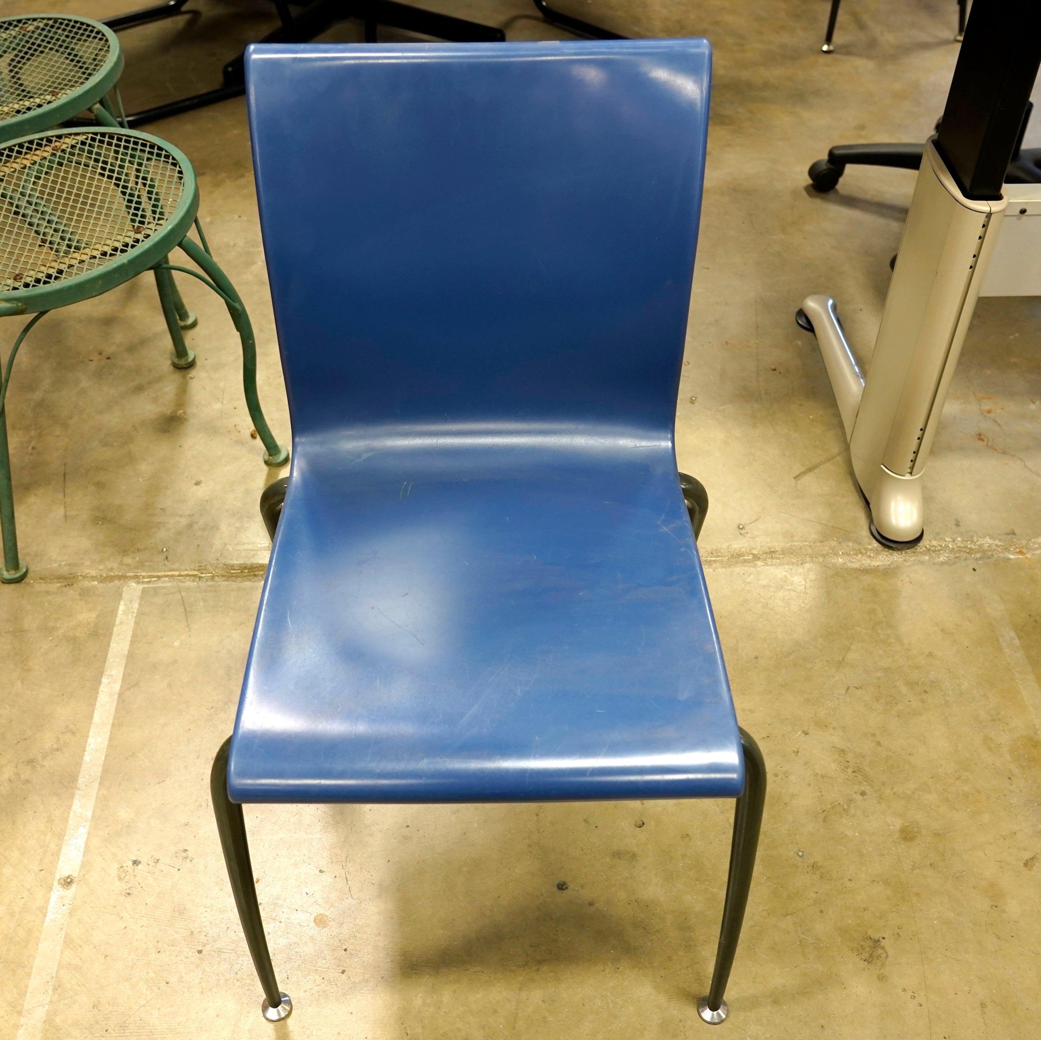 Blue institutional stacking chair featuring a molded plastic shell.