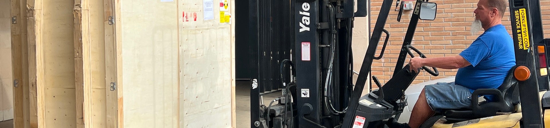 A Receiving Services worker uses a forklift to load a crate onto a loading dock.